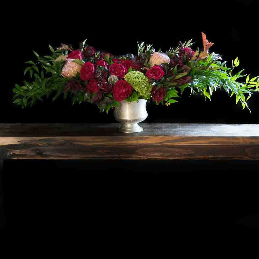 Christmas Holiday Flowers - flower arrangement with red roses, cones, and pink proteas