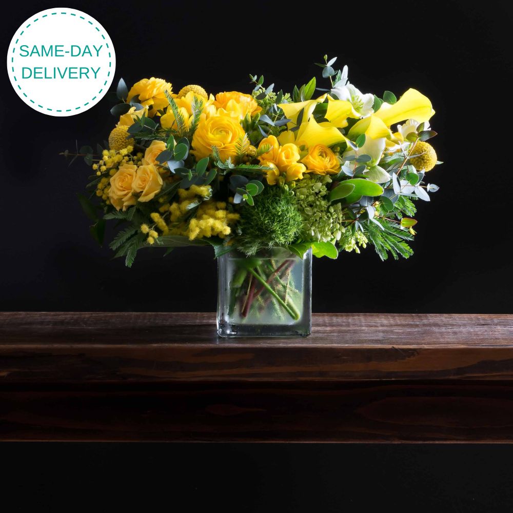 Beautiful boutique flower arrangement - yellow ranunculus, yellow calla lilies, light yellow spray roses, and mini green hydrangeas.