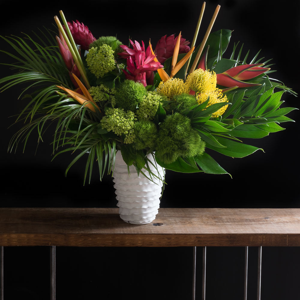 Tall tropical floral arrangement with burgundy, yellow, and red tropical flowers