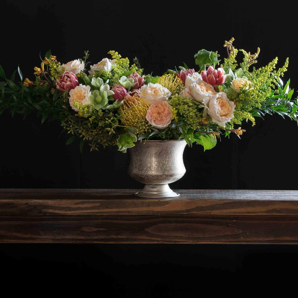 Boutique Luxe floral arrangement with blush roses, red tulips, hellebores, hydrangeas, and yellow balls