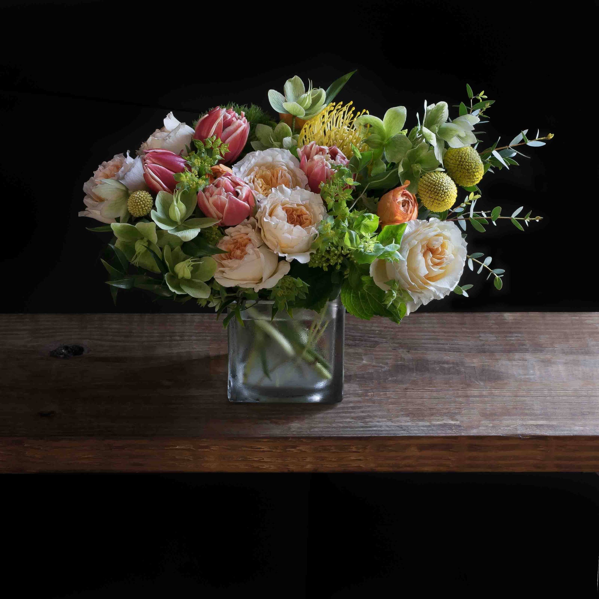 Beautiful floral arrangement with blush roses, red tulips, hellebores, hydrangeas, and yellow balls