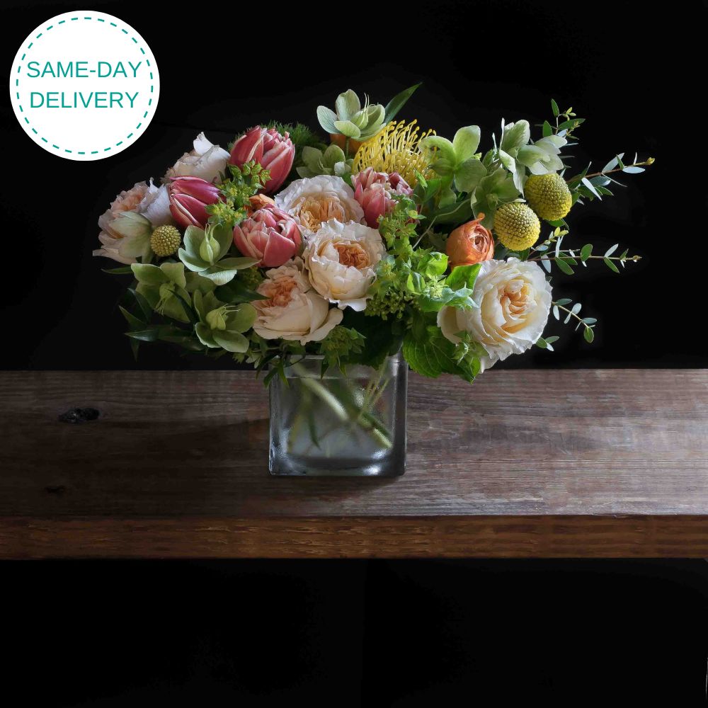 Beautiful floral arrangement with blush roses, red tulips, hellebores, hydrangeas, and yellow balls