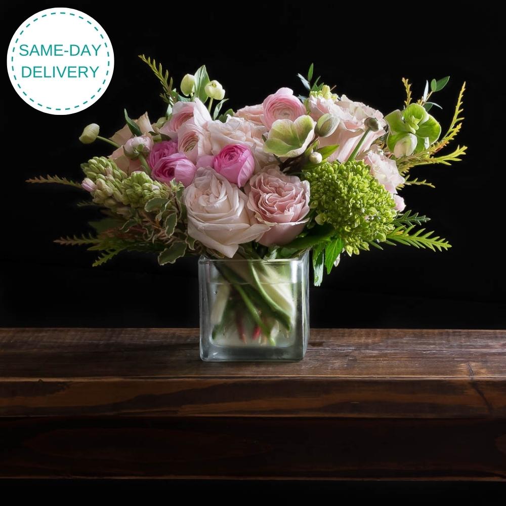 Beautiful unique boutique floral arrangement with light pink roses, fragrant garden roses, light pink ranunculus, and hyacinths.