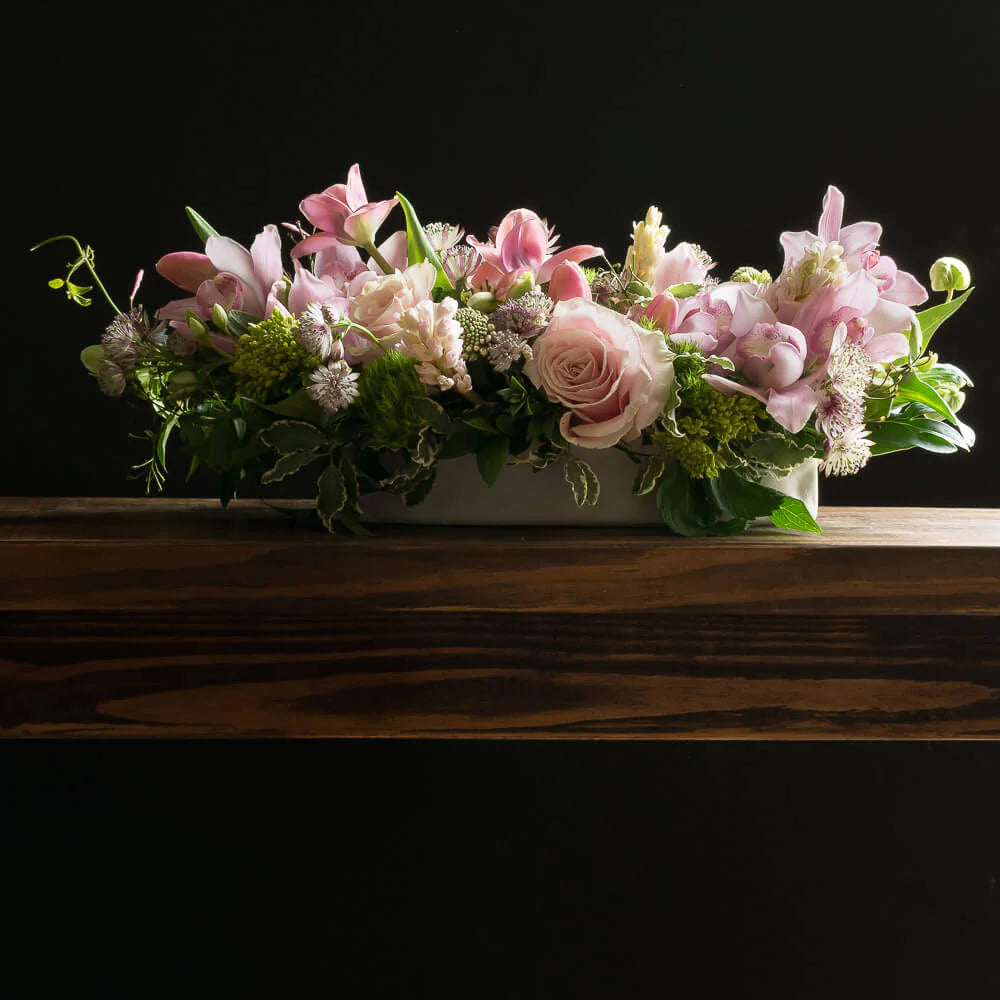 Beautiful unique boutique centerpiece floral arrangement with light pink roses, fragrant garden roses, light pink ranunculus, and hyacinths.
