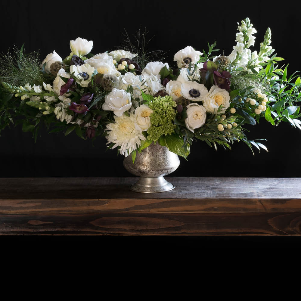Luxe Holidays floral arrangement with white roses, white anemones, burgundy hellebores.