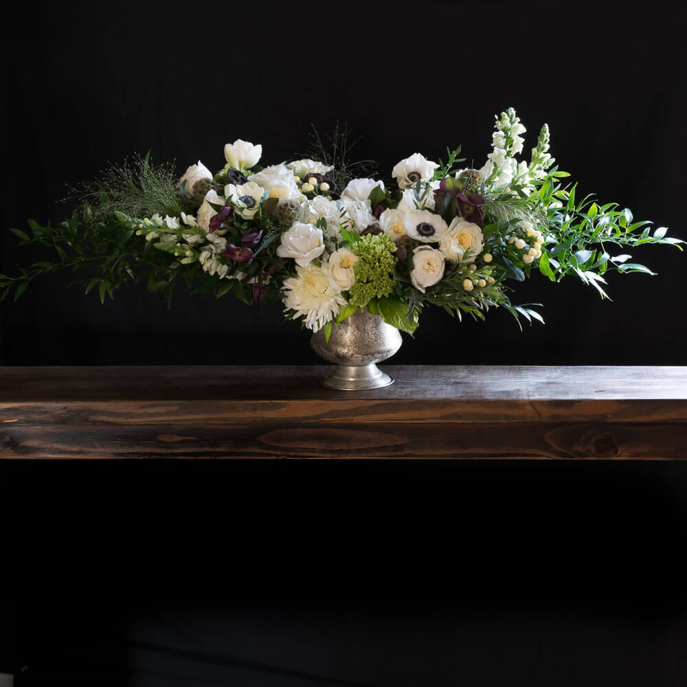 Luxe Holidays floral arrangement with white roses, white anemones, burgundy hellebores.