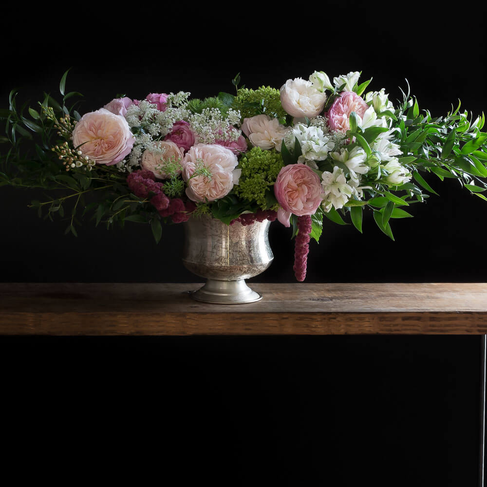 Beautiful luxe boutique floral arrangement with fragrant David Austin light pink garden roses, light pink small roses, white alstroemerias, and mini green hydrangeas.