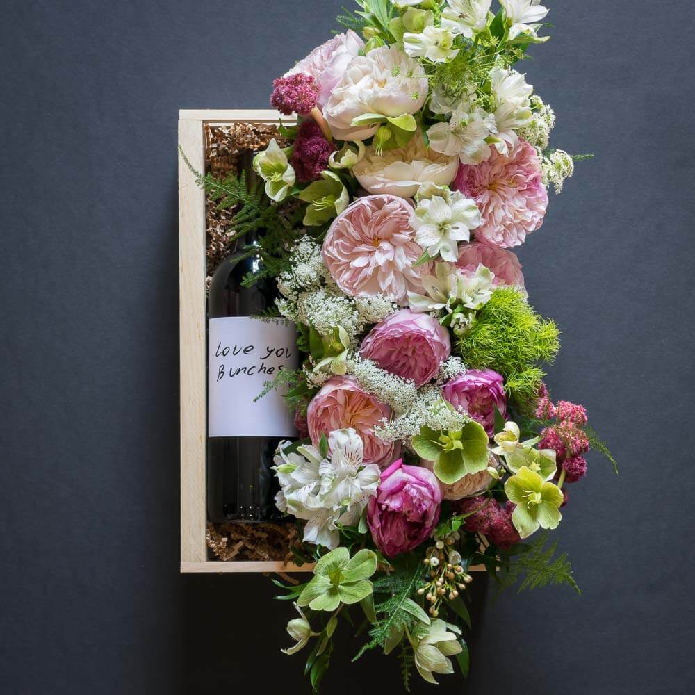 Jardin Floral gift box with fragrant David Austin light pink garden roses, light pink small roses, white alstroemerias, and mini green hydrangeas, and organic red wine