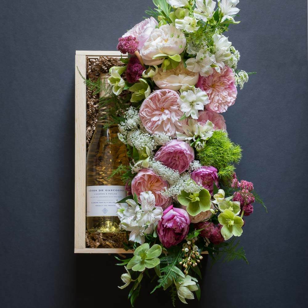 Jardin Floral gift box with light pink garden roses, light pink small roses, white alstroemerias, and mini green hydrangeas, and organic white wine