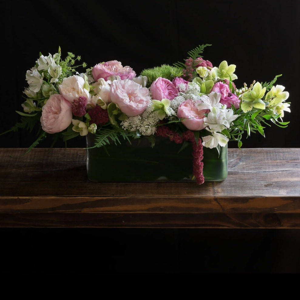 Beautiful boutique centerpiece with light pink garden roses, light pink small roses, white alstroemerias, and mini green hydrangeas.