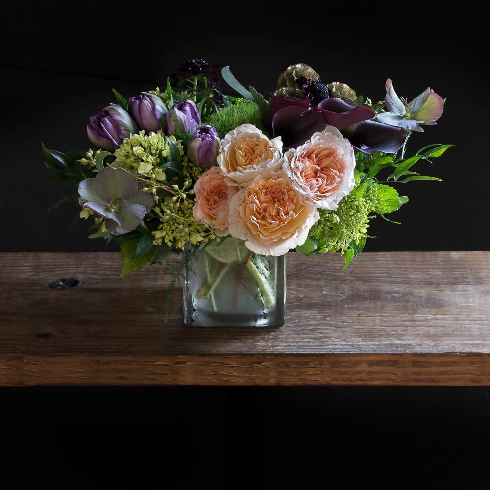 Jardin Floral arrangement with burgundy calla lilies, purple tulips, light orange fragrant David Austin Roses
