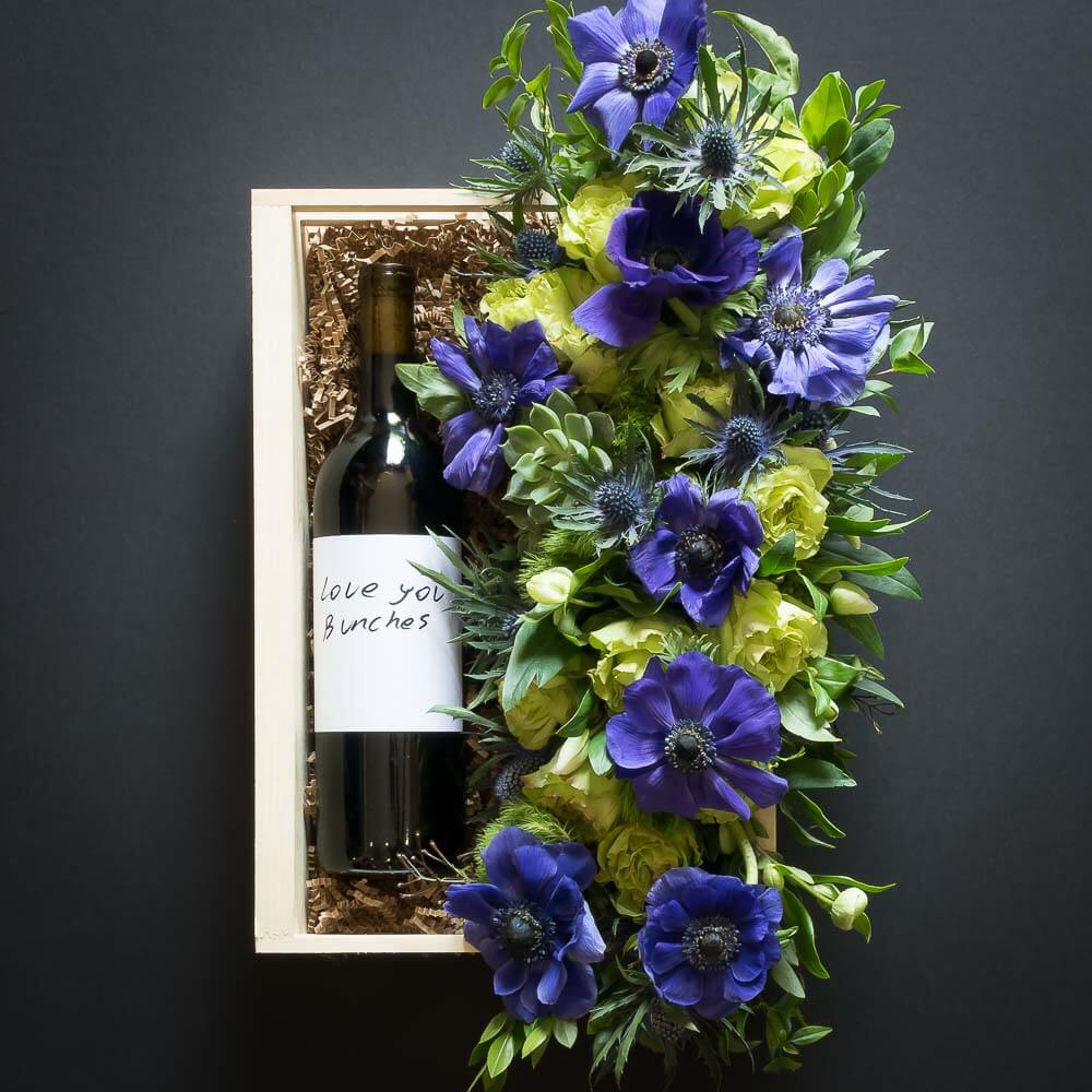 Floral Basket Gift Box boutique floral arrangemt with blue flowers, green roses and organic red sangiovese wine bottle