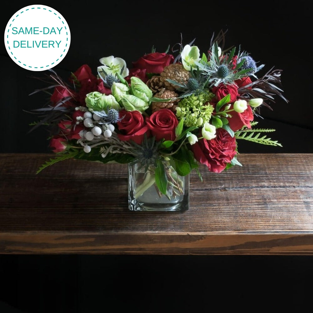 Unique Holiday Christmas floral arrangement of red rose, white parrot tulips, and cones.