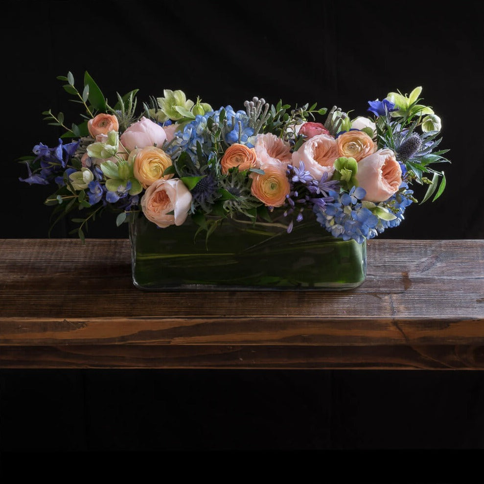 Jardin floral design centerpiece  with blush roses, blue flowers, hellebores, hydrangeas, with organic red wine