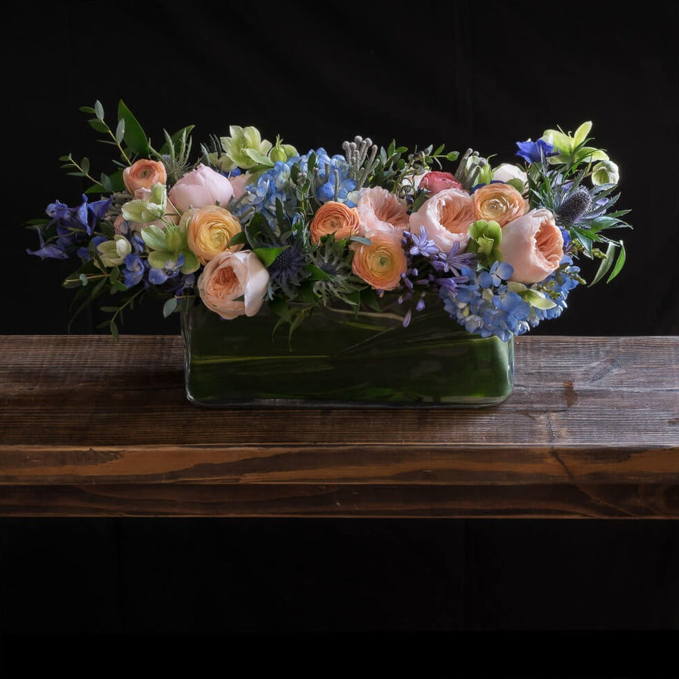 Beautiful centerpiece floral arrangement with blush roses, blue flowers, hellebores, hydrangeas