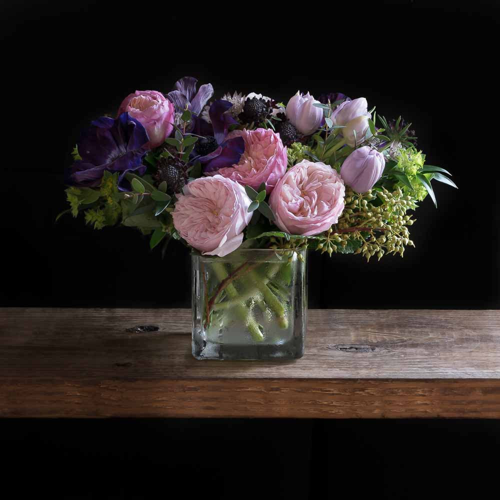 Unique floral arrangement with light pink David Austin garden roses, light pink small roses, purple anemonies, and mini green hydrangeas.