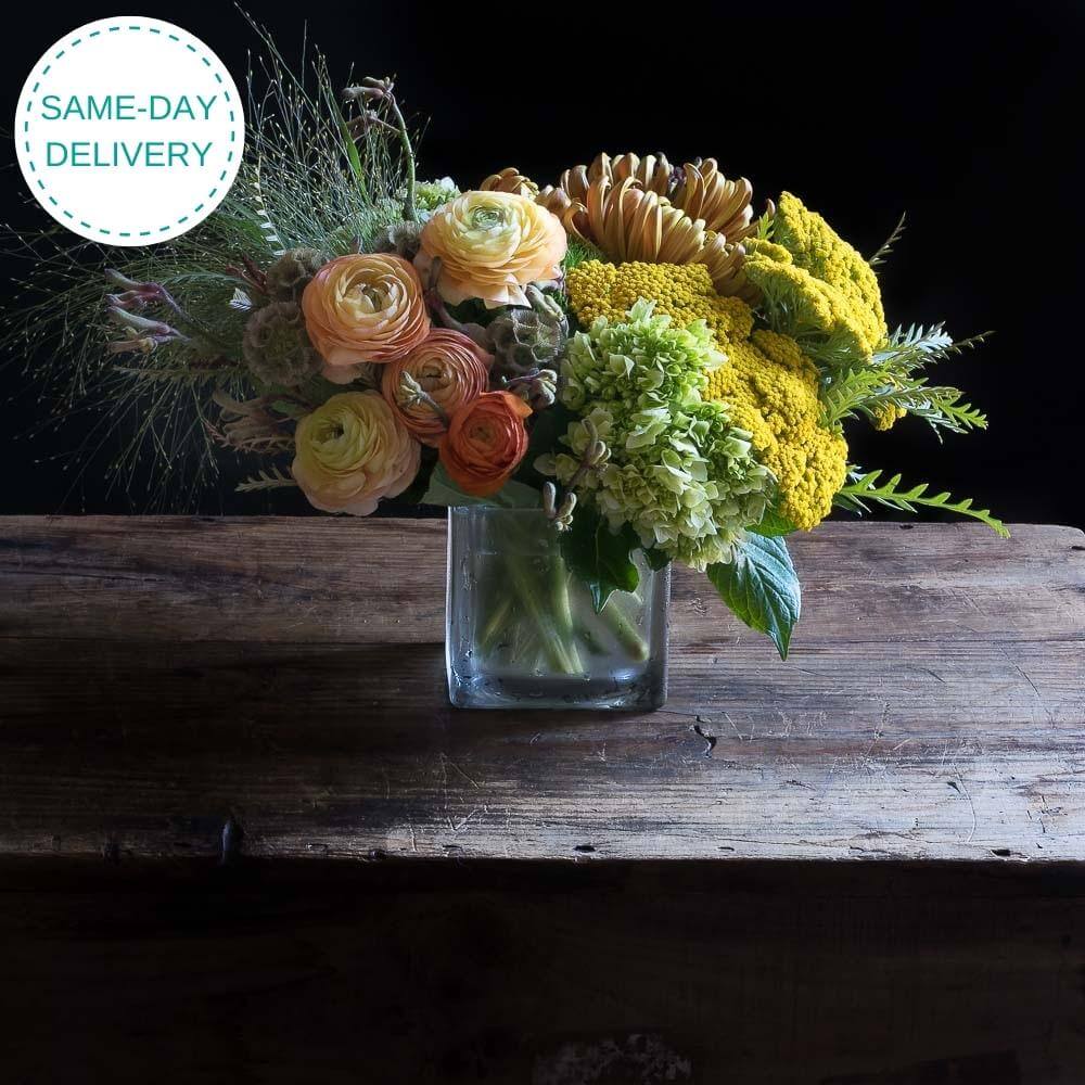 Top luxury colorful fall flower arrangement with light orange ranunculus, yellow flowers.