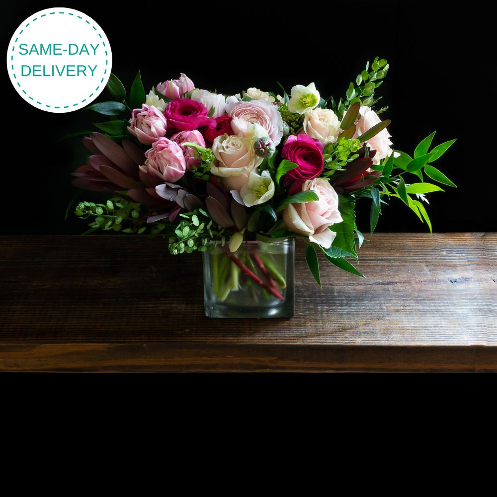 Unique boutique floral arrangement using the best premium flowers - light pink roses, red ranunculus, dark pink ranunculus, pink tulips, and mini hydrangeas.