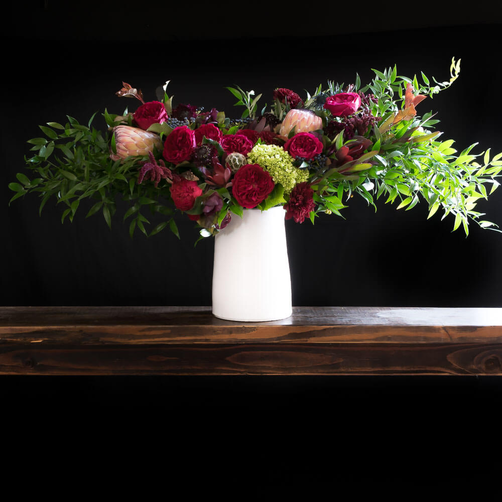 Boutique tall floral arrangement with red roses and other red flowers