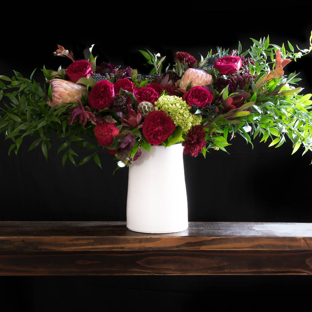 Boutique tall floral arrangement with red roses and other red flowers