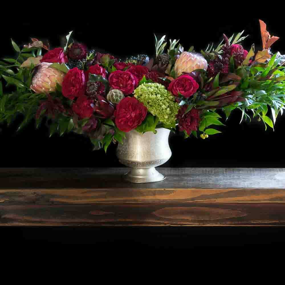 Christmas Holiday Flowers - flower arrangement with red roses, cones, and pink proteas