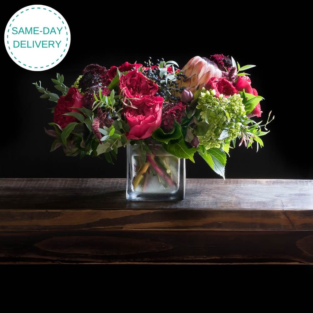 Christmas floral arrangement of red roses, light pink proteas.