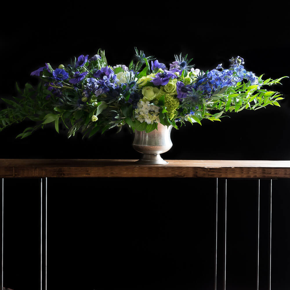 Unique blue, indigo, purple boutique floral arrangement of hydrangeas and anemones.
