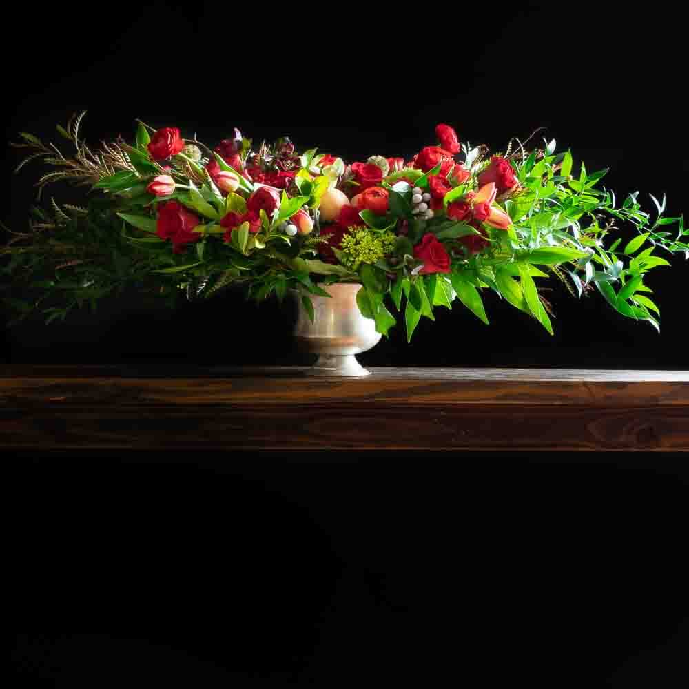 Luxury boutique floral arrangement of red flowers including red roses, red tulips, and red anemones