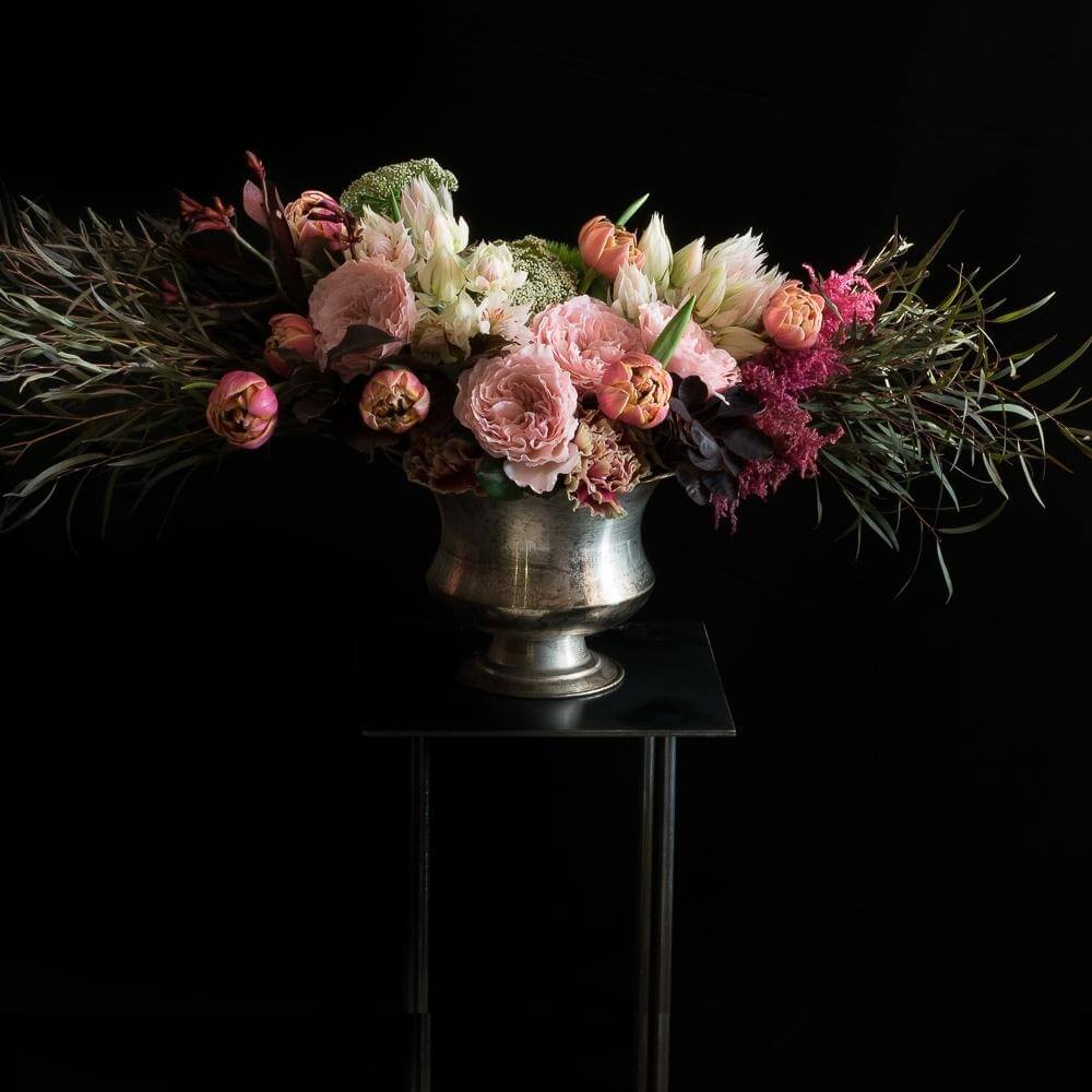 Boutique floral arrangement with pink fragrant garden roses, burgundy flowers, pink, orange tulips, and white flowers.