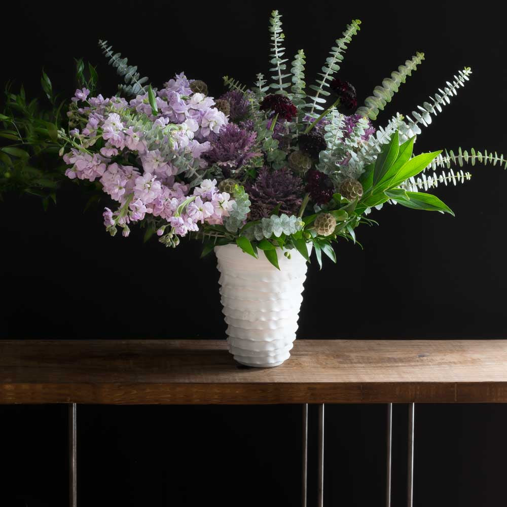 Tall floral arrangement with purple and burgundy flowers