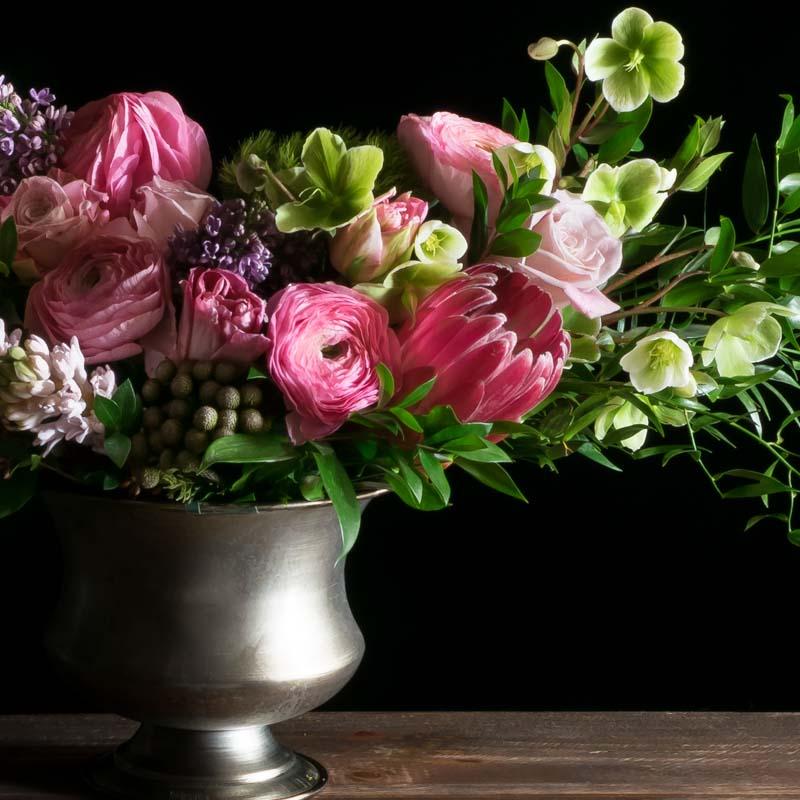 Beautiful luxe boutique flower arrangement with pink ranunculus, pink roses, and protea