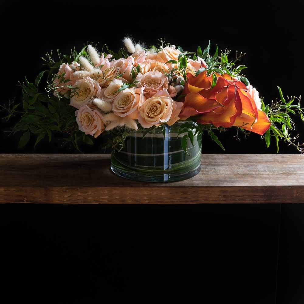 Unique boutique floral arrangement with peach roses and calla lilies