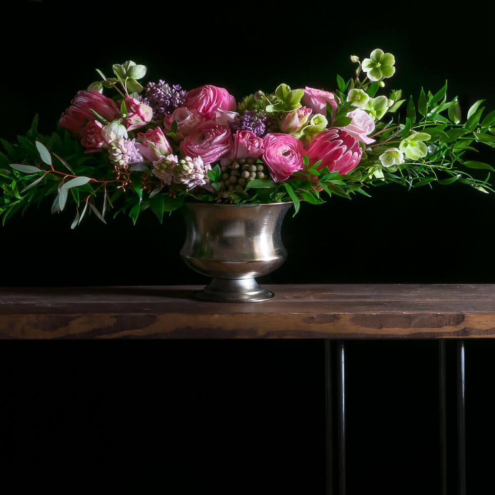 Beautiful luxe boutique flower arrangement with pink ranunculus, pink roses, and protea